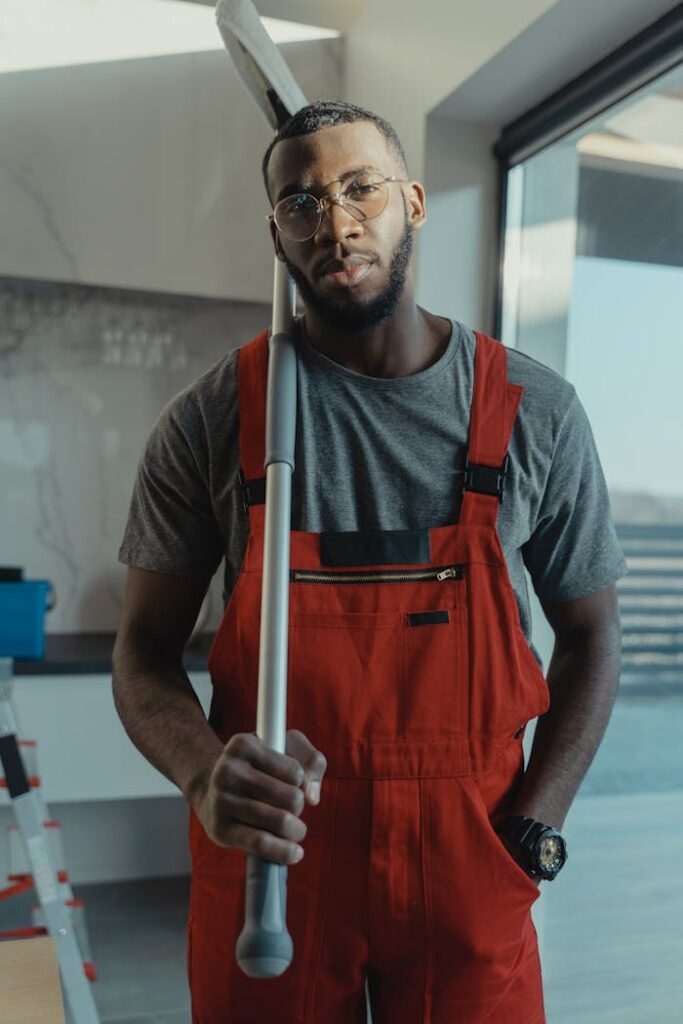 Confident male cleaner posing with cleaning tool in modern interior, showcasing professionalism.